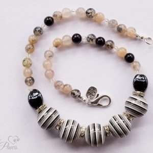 black and white striped round beads strung with oval black crystals and marbleized white glass beads on white background