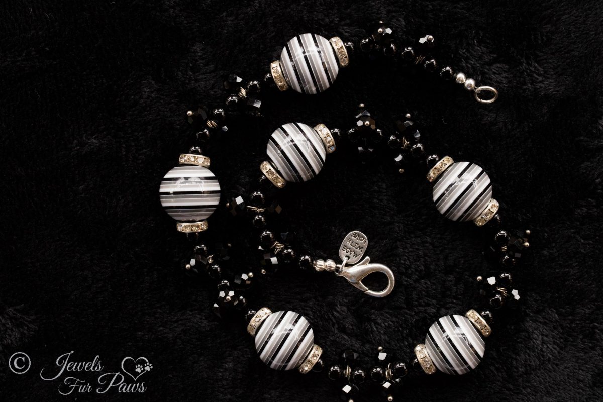 Six large black and white striped beads with black swarovski crystal clusters on black background