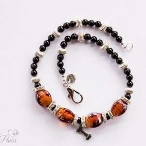 brown lampwork oval glass beads strung with silver rhondell spacers and channel set czech crystal spacers with a hanging silver dog charm on a white background