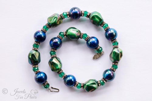 iridescent green bauble beads with iridescent blue pearl beads strung with green swarovski crystals and channel set rhinestone rondells on white background