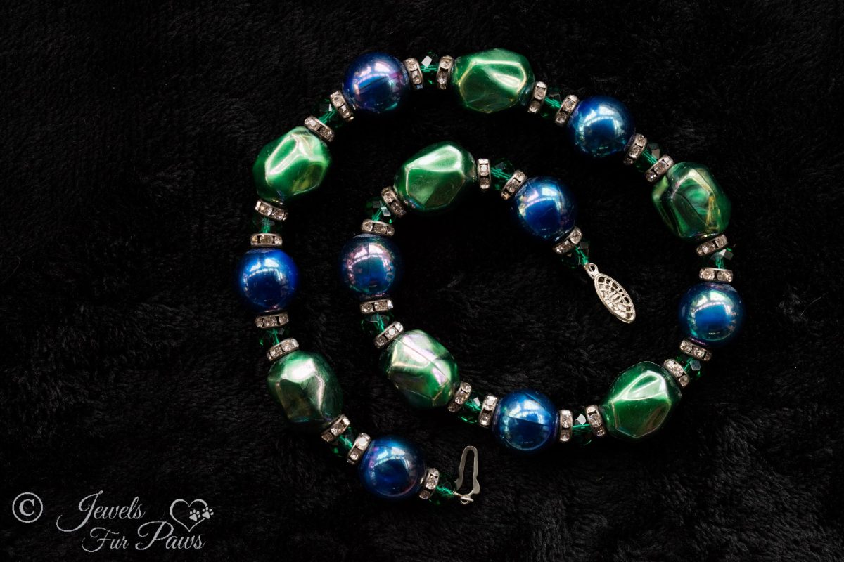 iridescent green bauble beads with iridescent blue pearl beads strung with green swarovski crystals and channel set rhinestone rondells on black background