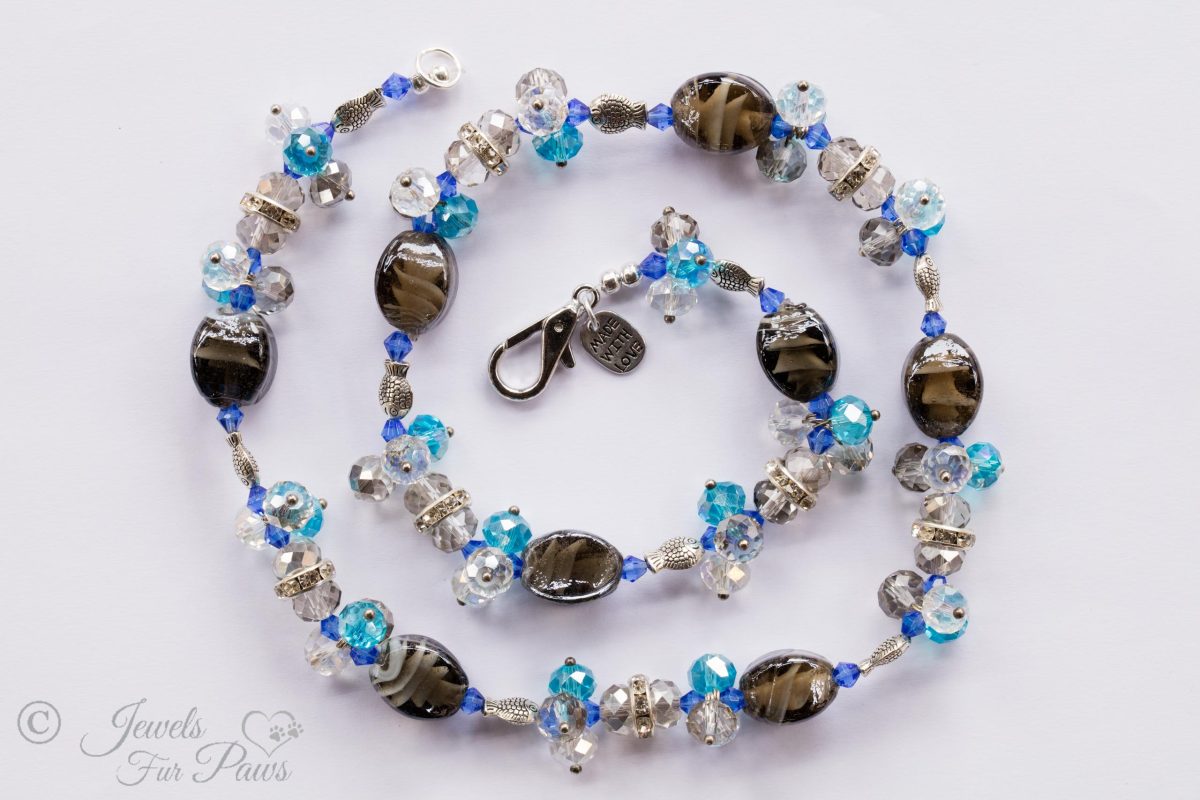 light brown tigers eye oval glass beads strung with different blue faceted Czech crystals and silver fish pet jewelry dog jewelry on white background