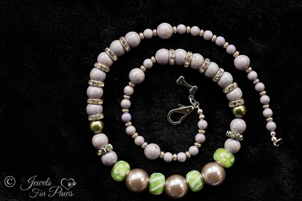 three large iridescent lavender silver pearl beads with green glass beads with swarovski channel set spacers and lavender beads on black background