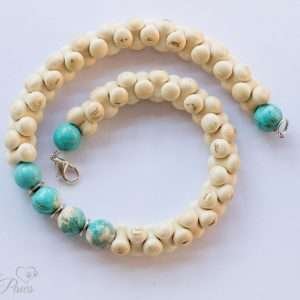 interlocking bone shaped beads surround four turquoise beads with turquoise end beads on white background