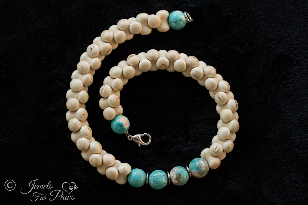interlocking bone shaped beads surround four turquoise beads with turquoise end beads on black background