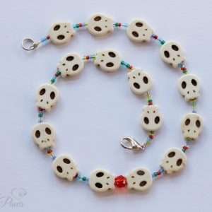 pet dog cat jewelry necklaces white skull charms strung with small blue, green, amber, orange spacer beads and feature a larger faceted red czech crystal on a white background