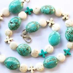 large oval turquoise beads with round flat howlite spacers and turquoise and howlite crosses on white background