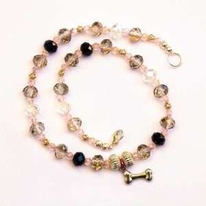 silver rhondells surround a hanging silver bone charm strung with light amber and light pink faceted crystals on white background