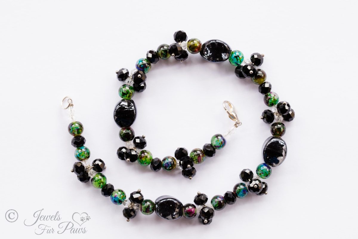 large black oval glass beads with clusters of black faceted Czech crystal and marble green beads on white background for medium dogs pet jewelry
