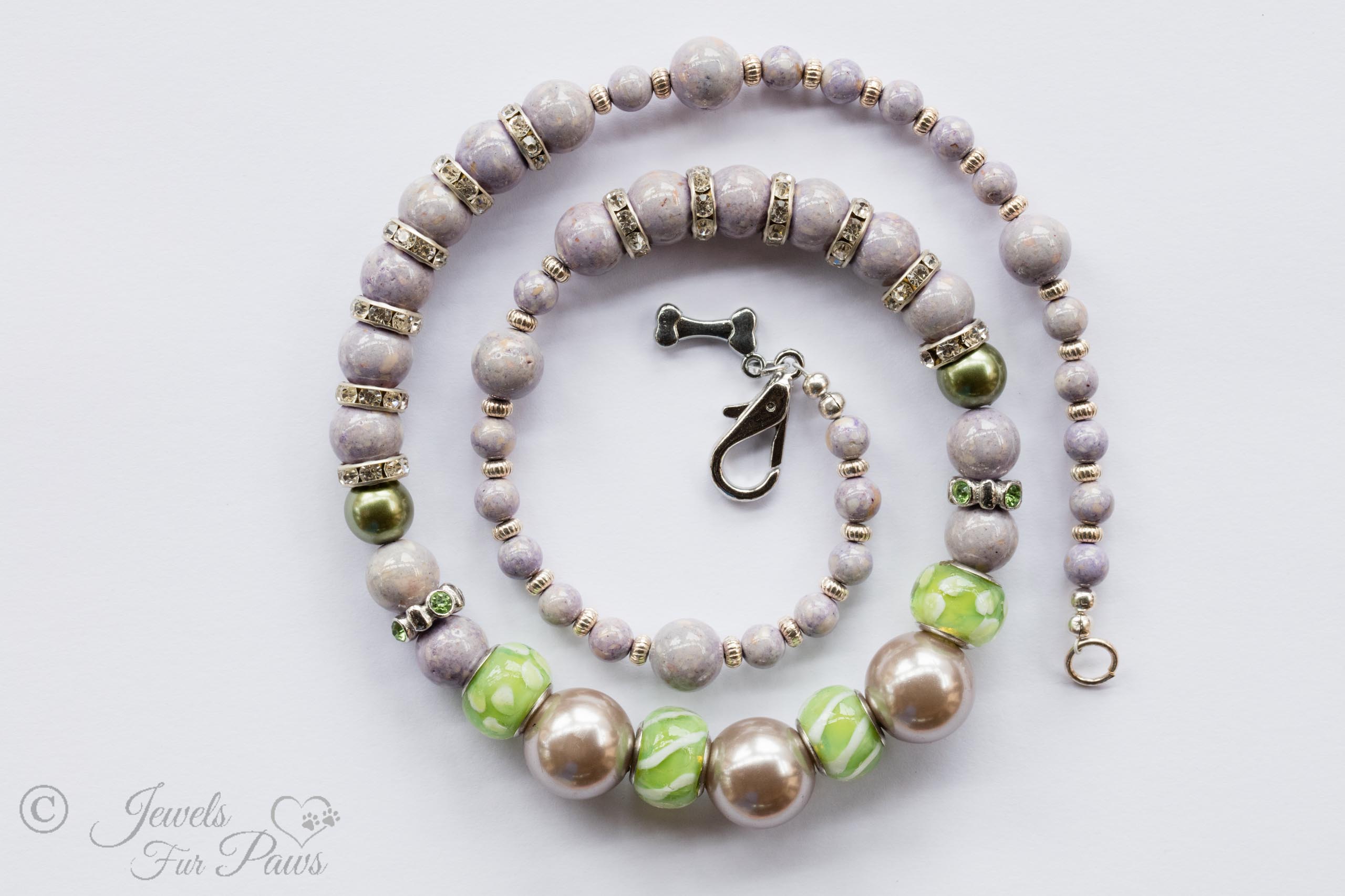 three large iridescent lavender silver pearl beads with green glass beads with swarovski channel set spacers and lavender beads on white background