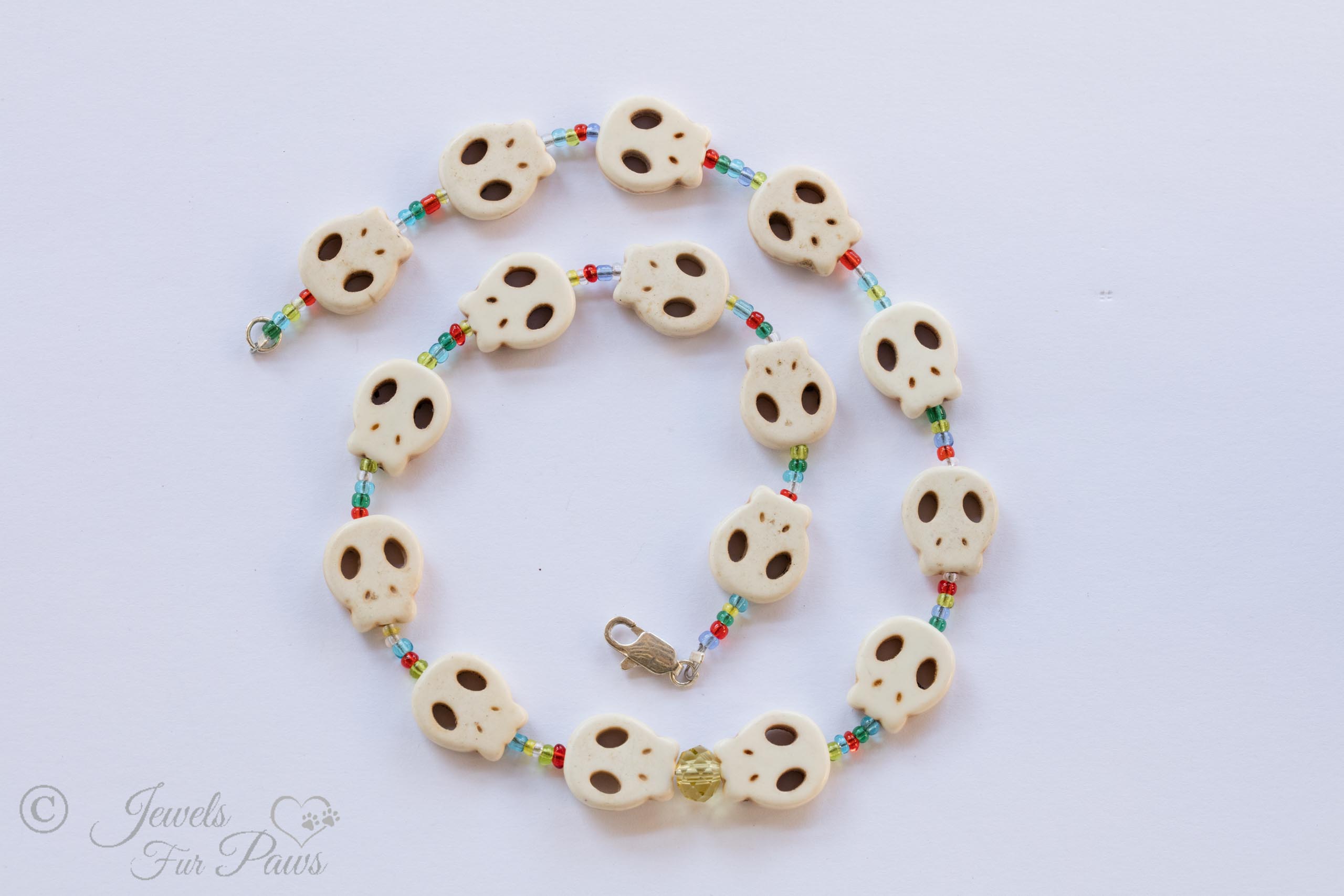 dog cat pet necklaces jewelry, off-white skull shaped beads with different colored spacers and an amber Czech crystal in the middle for on a white background