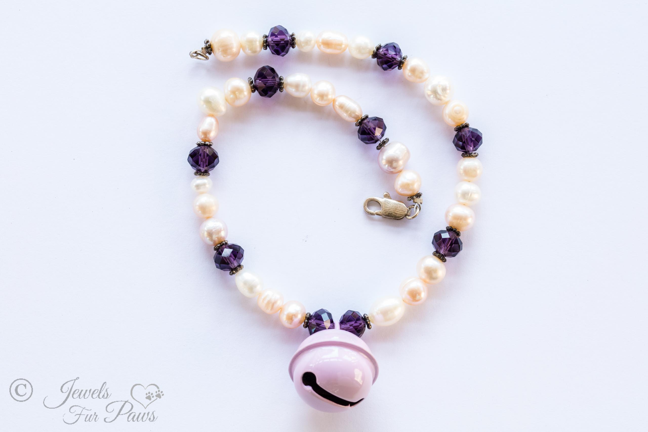 cultured pearls with amethyst beads and a lavender hanging bell on a white background