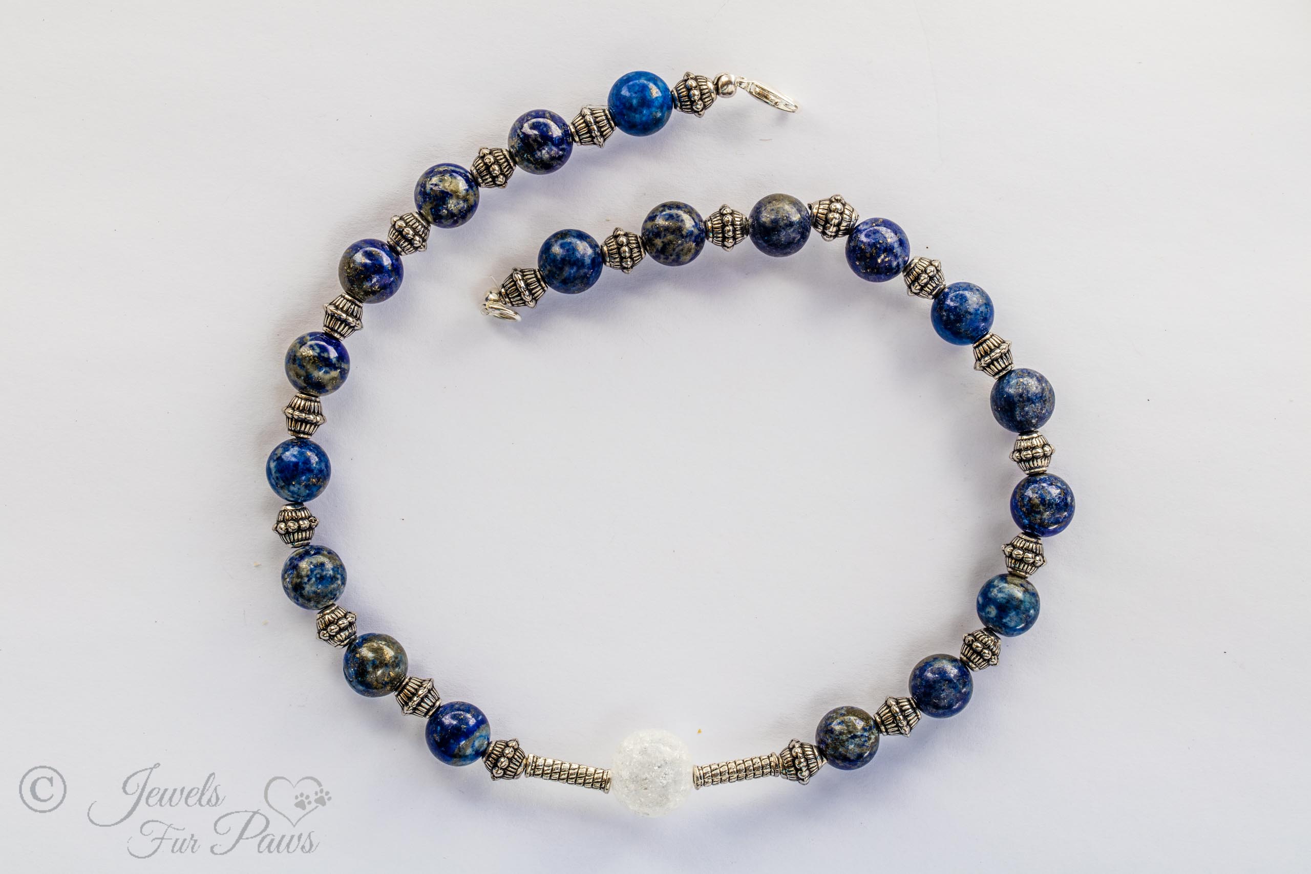 blue lapis lazuli necklace with cracked glass bauble in center on white background