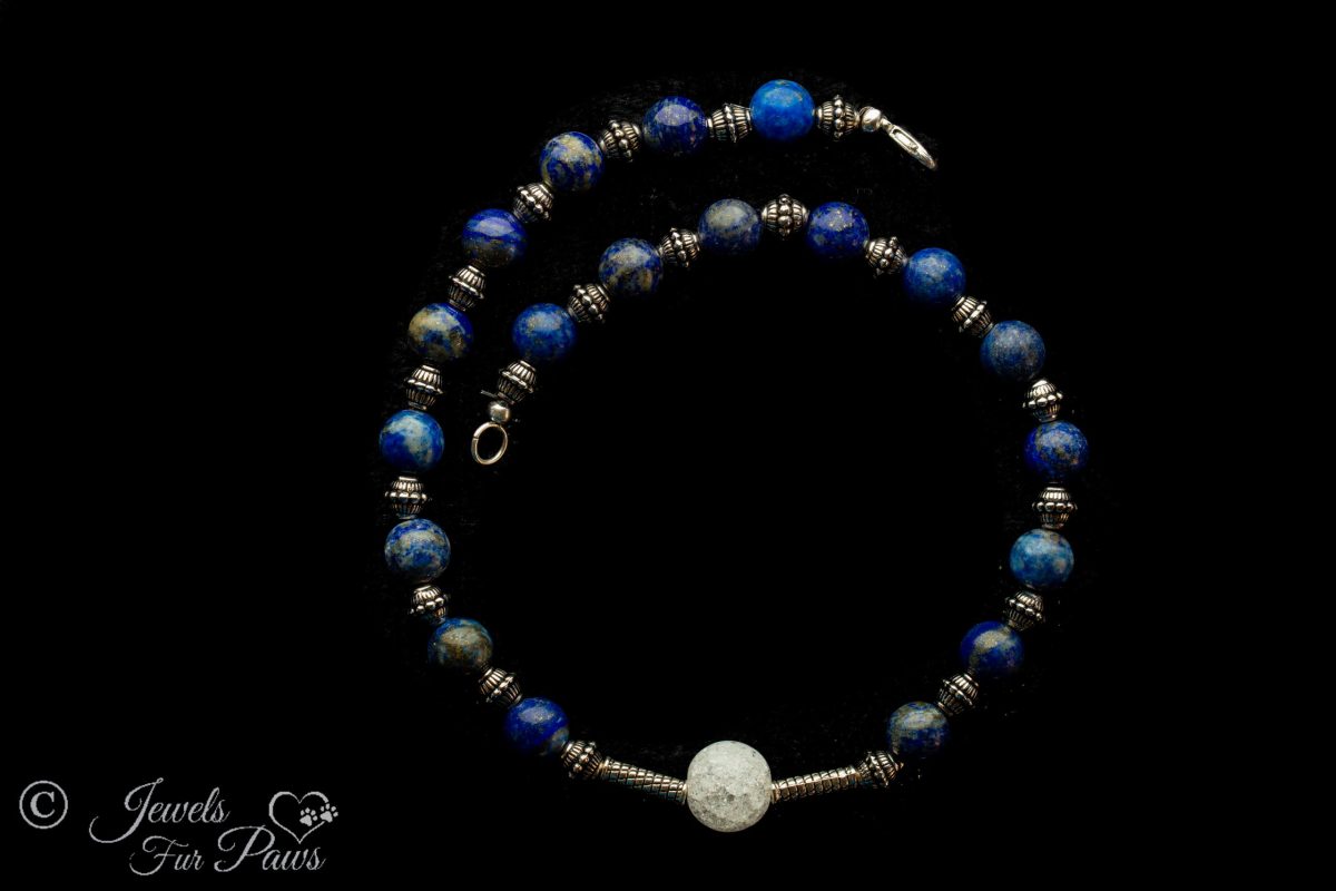 blue lapis lazuli necklace with cracked glass bauble in center on black background