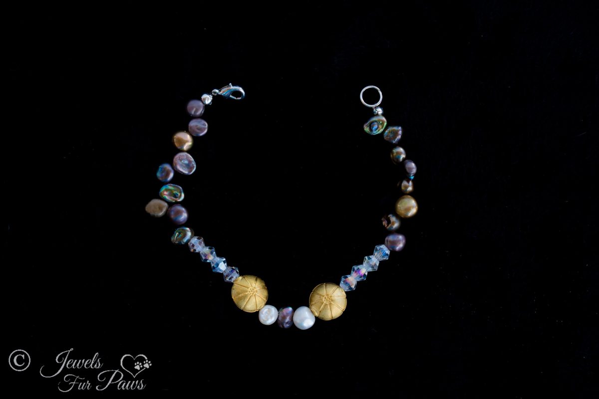 extra small pet necklace featuring different colored cultured freshwater pearls and czech crystals with 2 antique gold plated beads on a black background