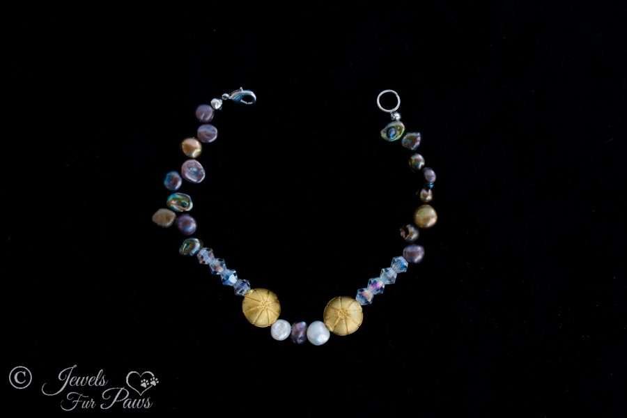 extra small pet necklace featuring different colored cultured freshwater pearls and czech crystals with 2 antique gold plated beads on a black background