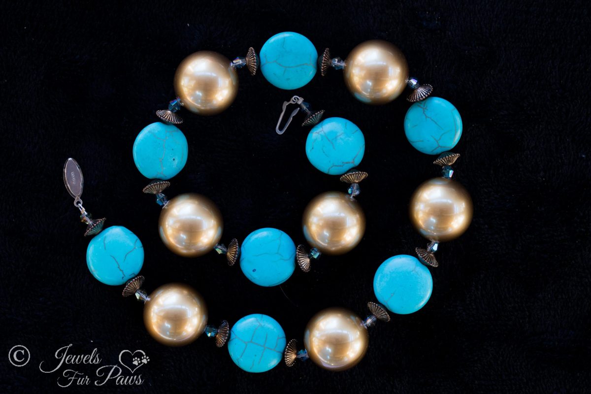 large gold pearl beads with silver rondell spacers and flat turquoise disc beads on black background