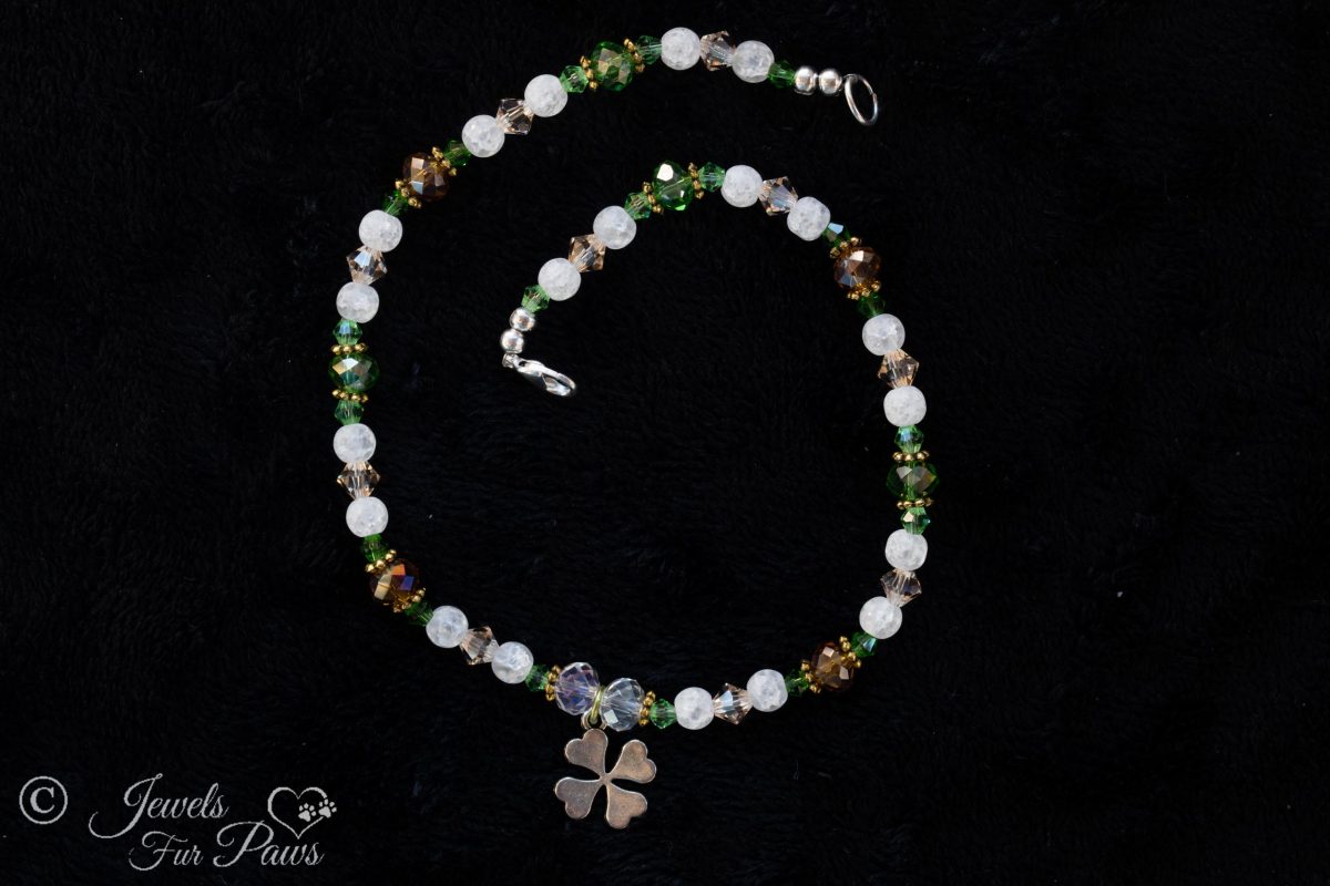 dog cat pet necklace green, white and amber beads with silver hanging lucky shamrock four leaf clover charm on black background